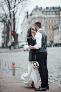 Full length of bridegroom embracing on street