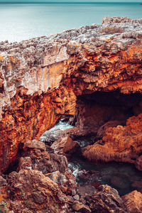 Rock formation on sea shore against sky