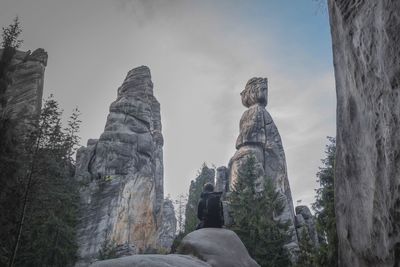 Low angle view of woman standing on rock against sky