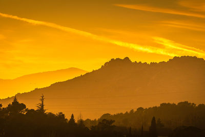 Scenic view of silhouette mountains against orange sky