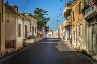 Road amidst houses against sky