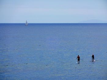 High angle view of people paddleboarding on sea against clear sky