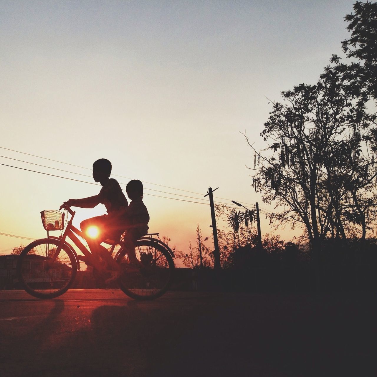 SILHOUETTE OF MAN RIDING BICYCLE AT SUNSET