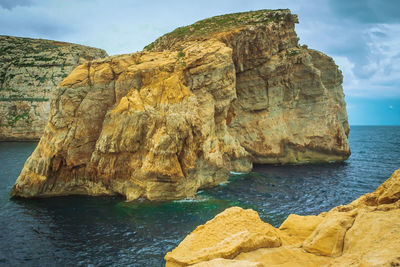 Scenic view of rock formation in sea against sky