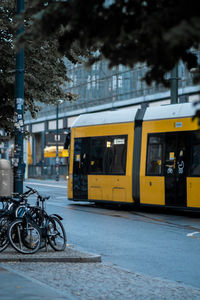 Bicycles parked on street in city with yellow tram passing through