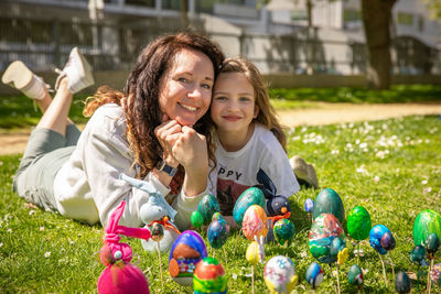 Portrait of smiling mother and daughter sitting on field