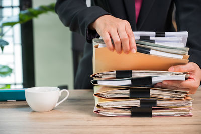 Midsection of man holding coffee cup on table