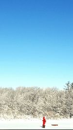 Snow covered field against clear blue sky