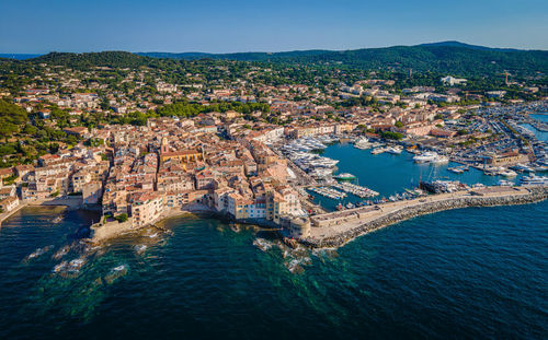 High angle view of townscape by sea against blue sky