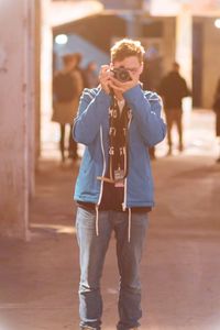 Young man photographing through camera while standing on road