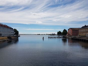 Buildings by river against sky