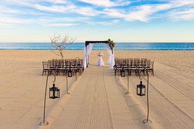 Chairs and decoration at beach against sky