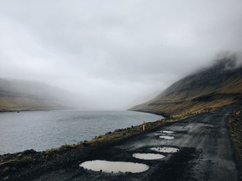 Scenic view of road by mountains against sky