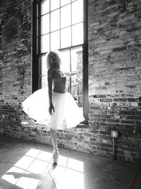 Ballet dancer practicing by window at dance studio