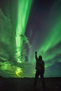 Woman standing by tree against sky at night