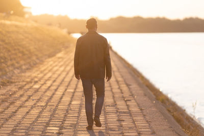 Single man walking away into sunset