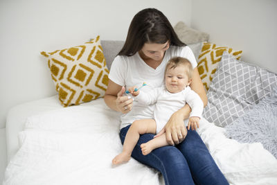 Mother and daughter sitting on bed at home