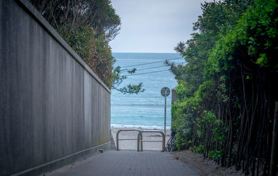 Walkway by sea against sky