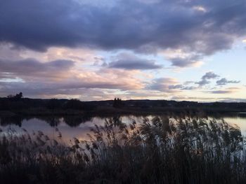 Scenic view of calm lake against cloudy sky