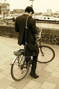 Rear view of man with bicycle on road in city