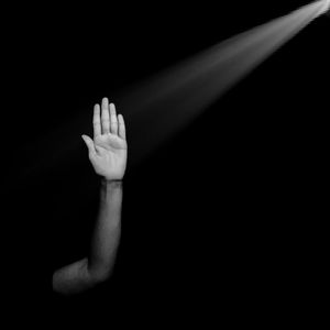 Light falling on man showing stop gesture against black background