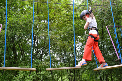 Adventure climbing high wire park - people on course in mountain helmet and safety equipment.