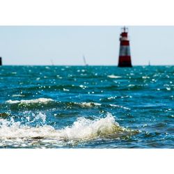 Lighthouse in sea against blue sky