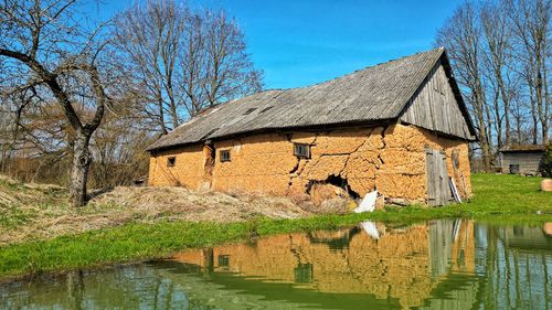 House by lake against sky