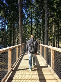 Full length rear view of man walking on footbridge