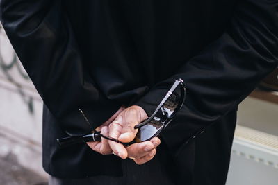 Midsection of man holding sunglasses