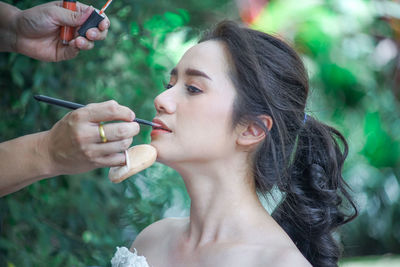 Close-up of person applying make-up on woman face