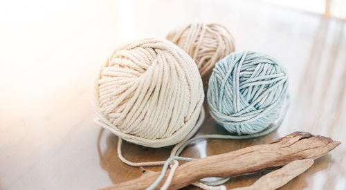 Balls of white and beige yarn on light wood table. threads of high-quality wool for macrame.