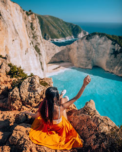 High angle view of woman sitting on rock by sea