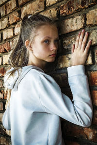 Portrait of teenage girl standing against wall