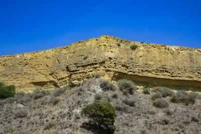 Low angle view of stone wall against clear blue sky