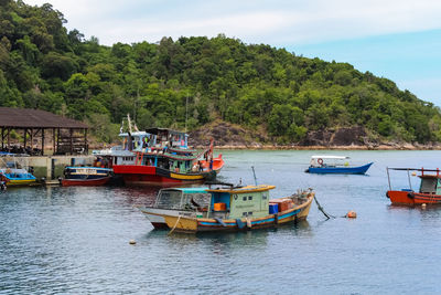 Boats moored at harbor against sky