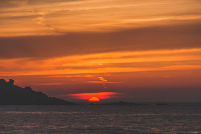 Scenic view of sea against dramatic sky during sunset