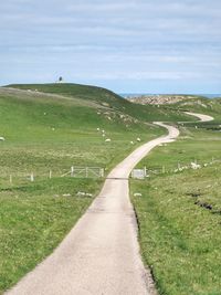 Road amidst field against sky