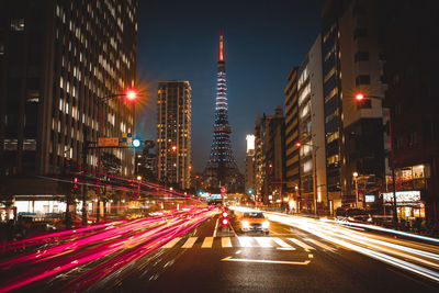 Light trails on city street amidst buildings at night