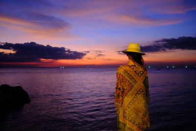 Rear view of man standing on beach during sunset