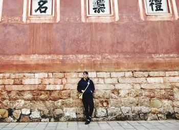 Full length of man standing against wall