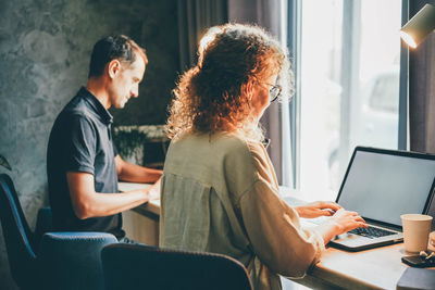 Side view of woman using laptop at home