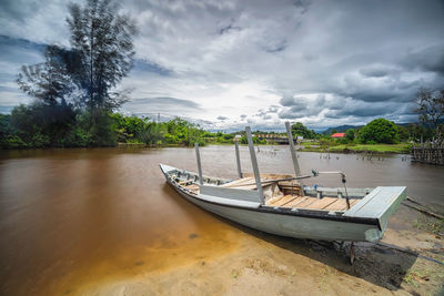 Boat moored on shore against sky