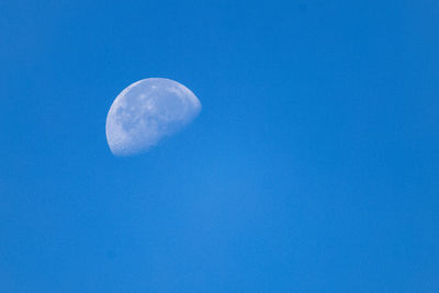 Low angle view of moon against clear blue sky