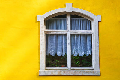 Closed wooden window on an yellow wall