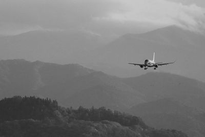 Airplane flying over mountains against sky