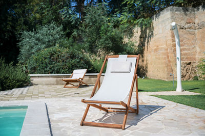 Swim pool with clear blue water and two sun bed on sunny day in a yard