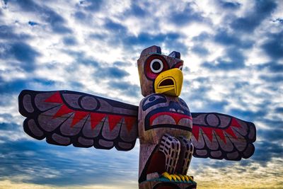 Low angle view of wooden statue against cloudy sky