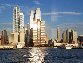 Sea by modern buildings against sky in city