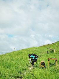People relaxing on field against sky
